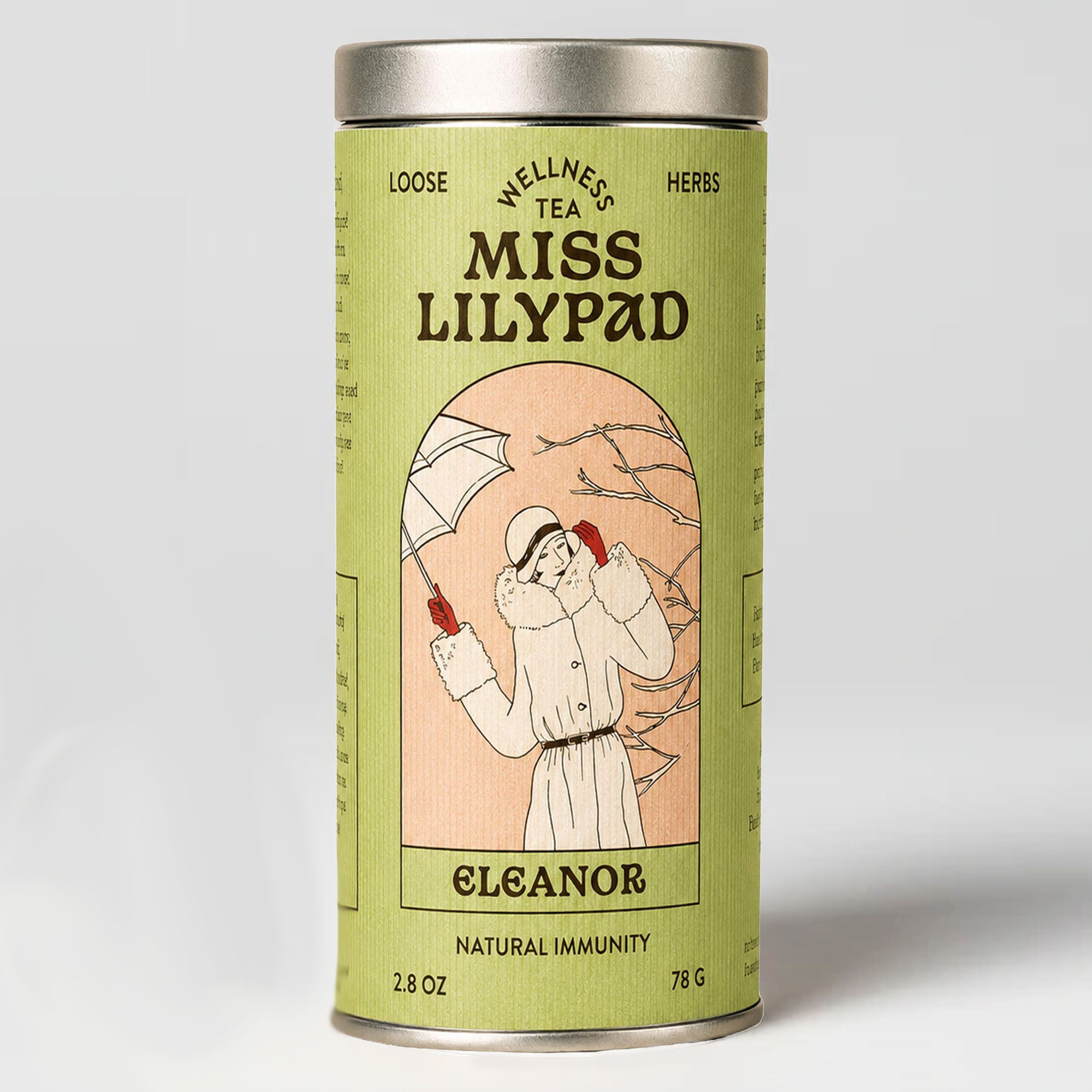Miss Lilypad  Natural Immunity Eleanor loose herbal tea in a cylindrical tin canister with a green label and silver metal lid and base. An illustration of a woman wearing a fur collar winter jacket , a hat  and red gloves holding an umbrella 